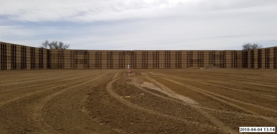 A completed and bermed well pad enclosed by sound walls after reclamation work