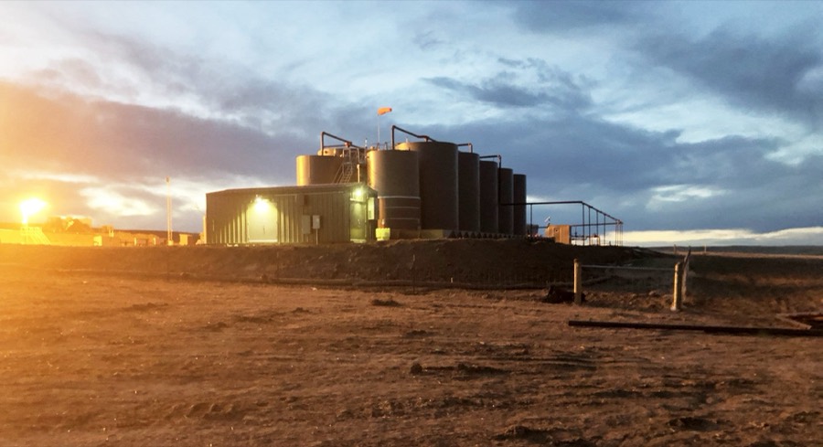 A produced water tank battery lit at dusk on the northern Colorado plains